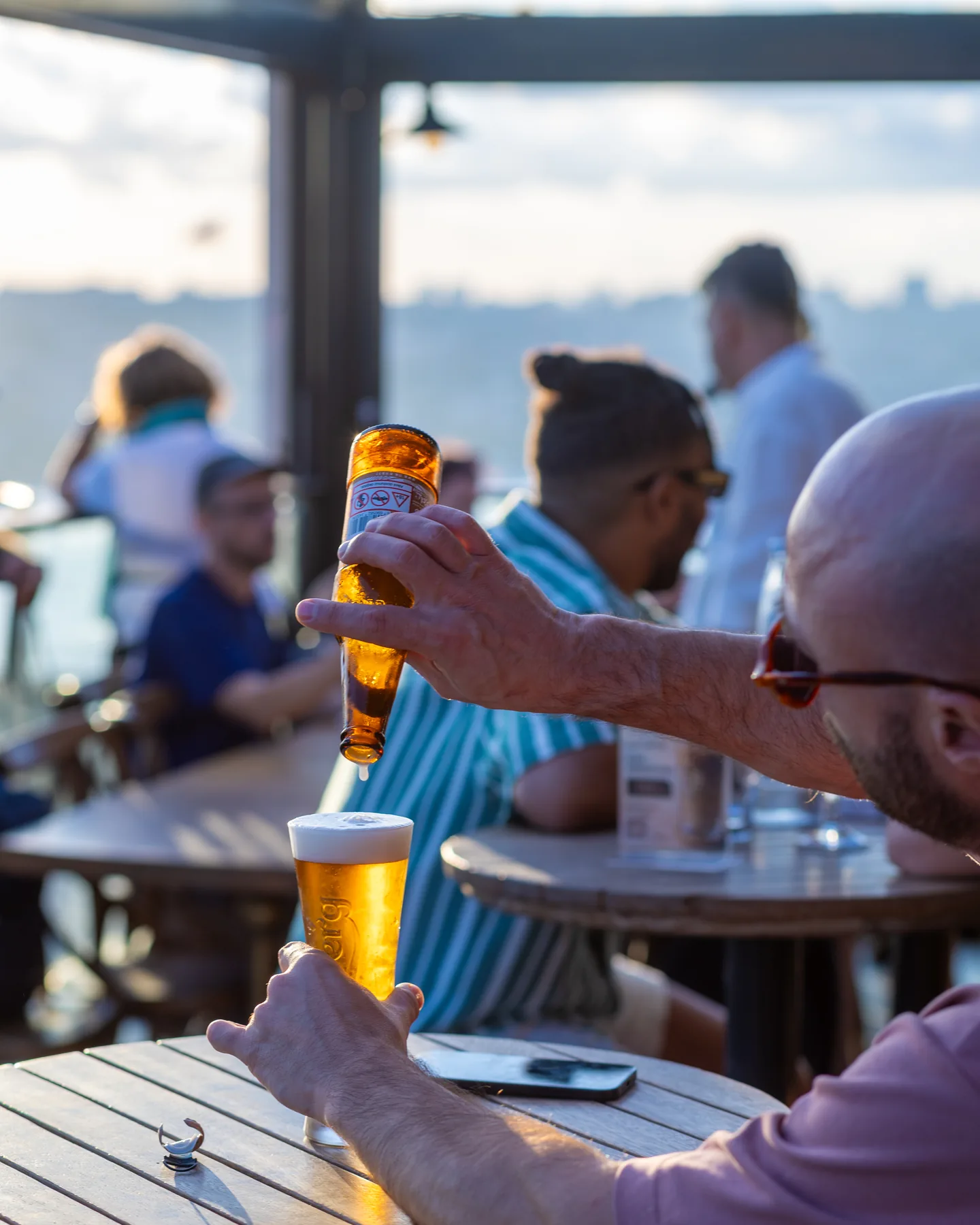 Balkon’da bir misafirin bardağına bira doldurulurken