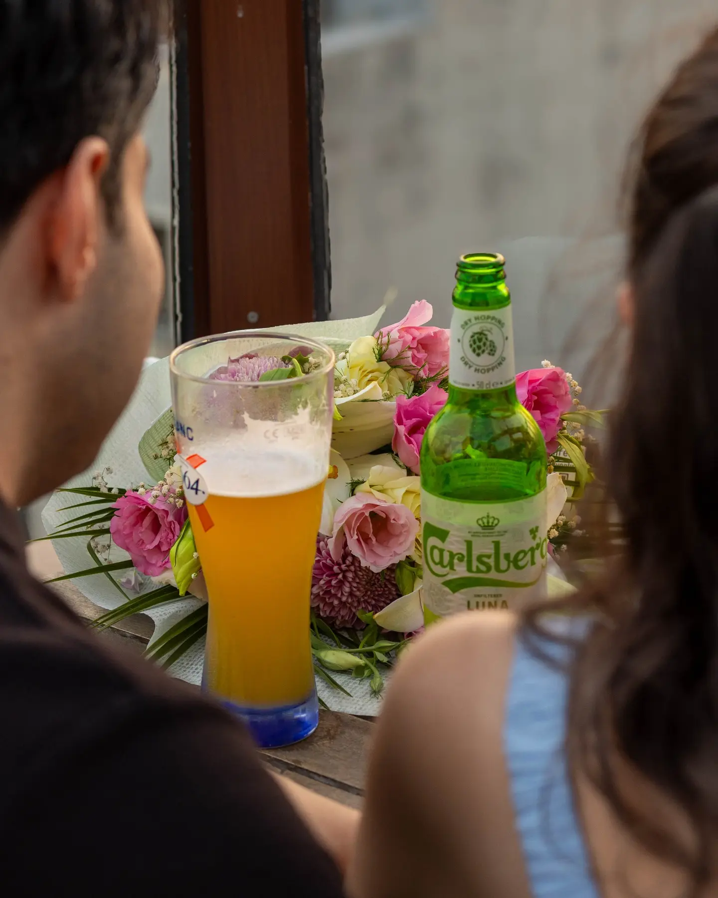 Balkon masasında çiçekler, bira ve misafirler