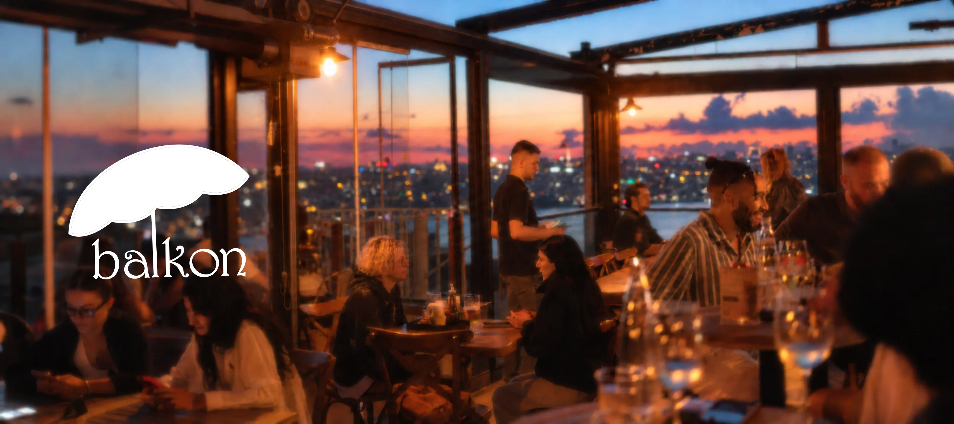 Balkon logosu; gün batımında dolu teras ve İstanbul’un ışıkları